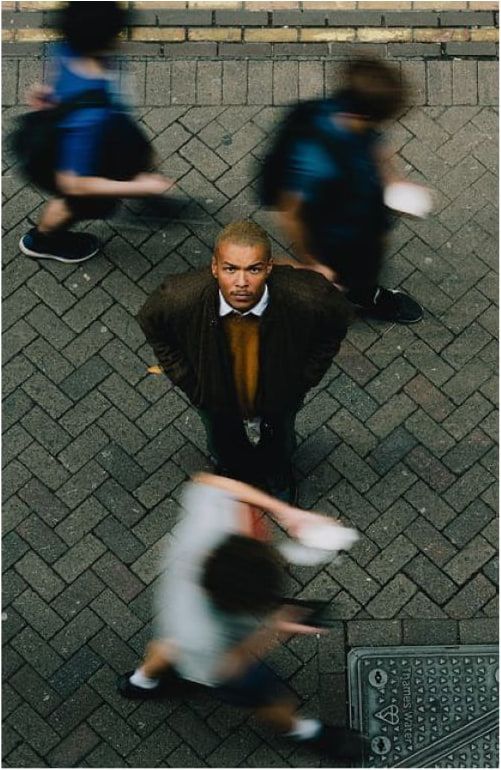 Blurred passers-by around a still man looking into the camera